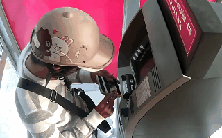 Người đàn ông đầu đội mũ bảo hiểm hình gấu Brown và thỏ Cony đáng yêu, tay gắn máy đọc trộm thông tin tài khoản tại cây ATM trong giây lát. Nguồn: Agribank.