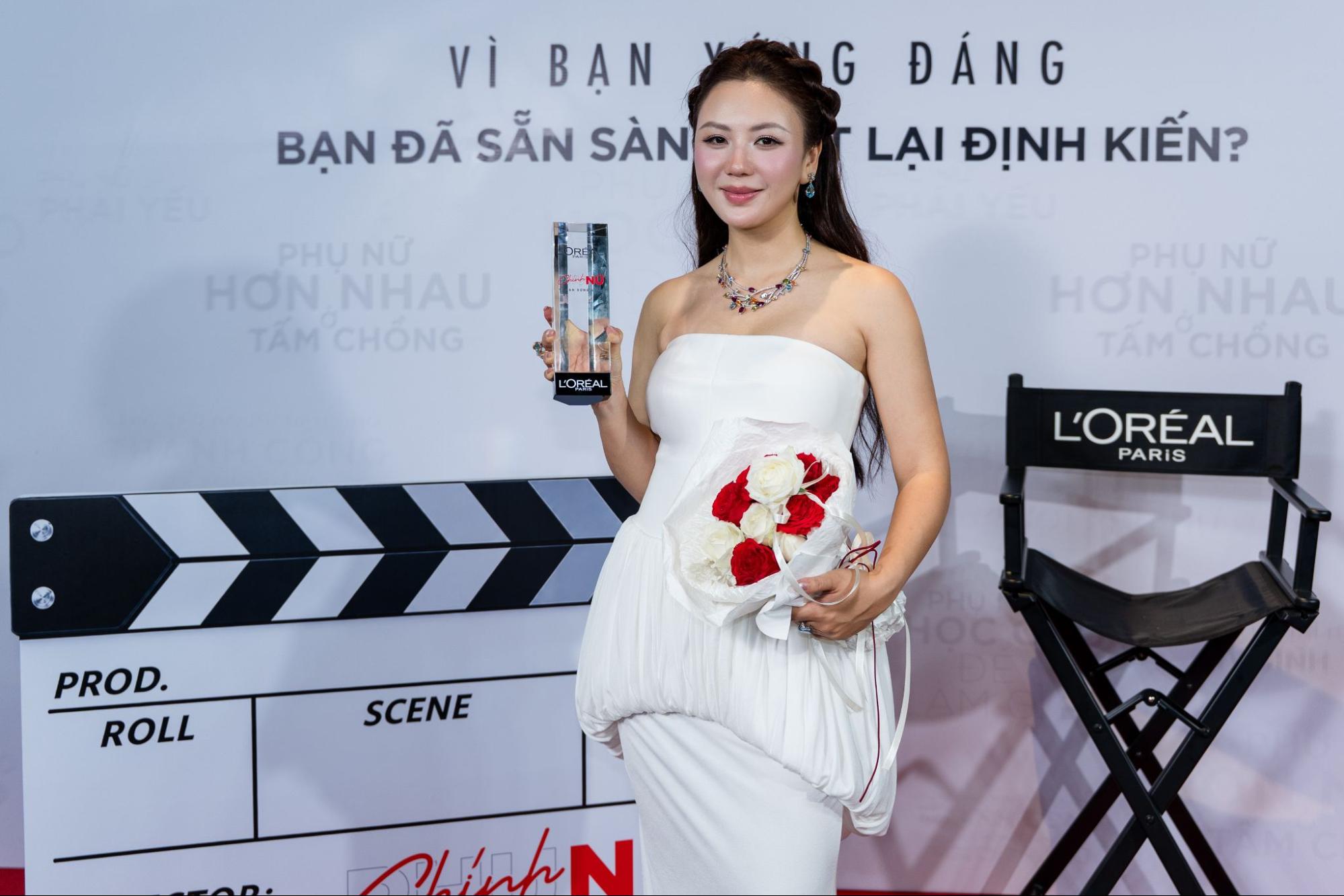 Chính Nữ trong đầm trắng cầm kỷ niệm chương